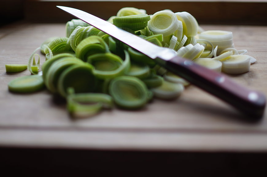 Sliced leeks and knife on wooden cutting board