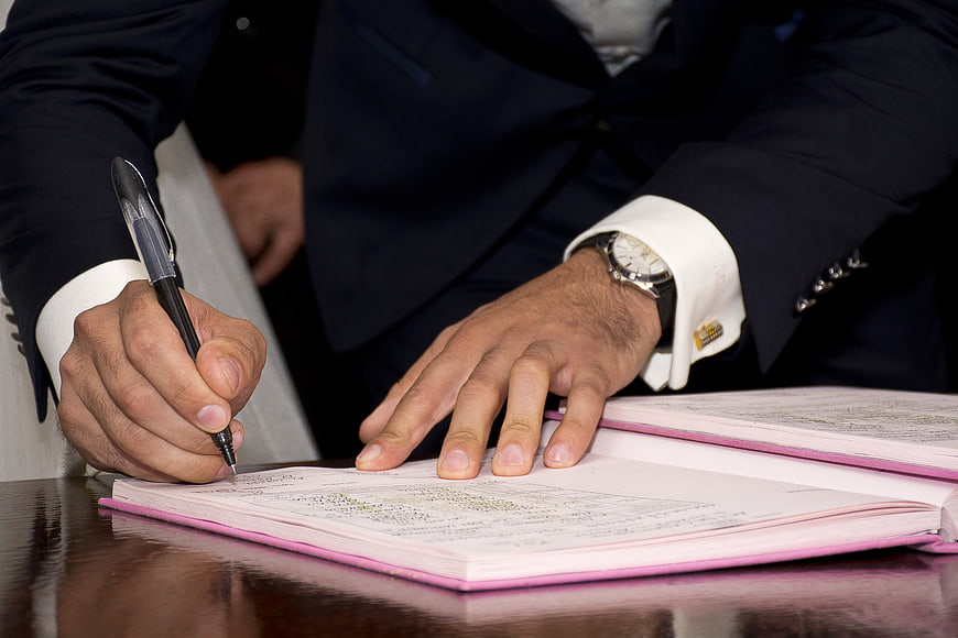 Man in Suit Signing Marriage Register with Pen