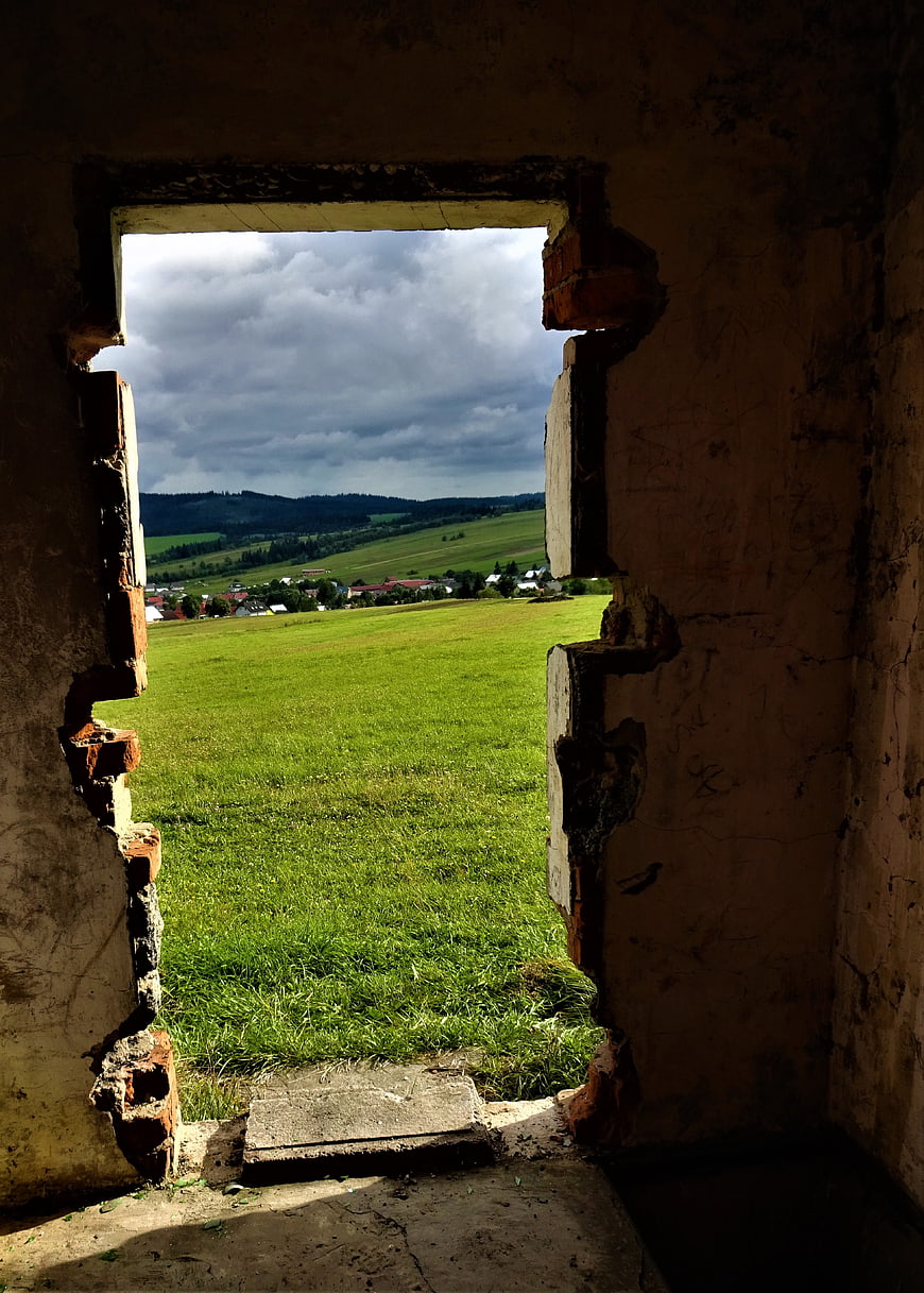 View of green countryside through ruined brick window