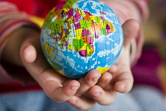 Child holding small colorful globe in cupped hands