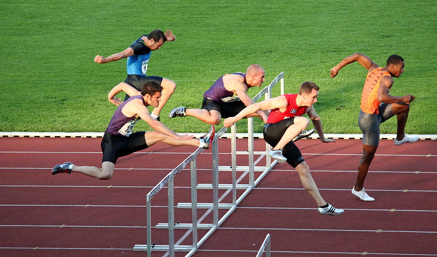 Male Athletes Competing In Hurdle Race On Outdoor Track