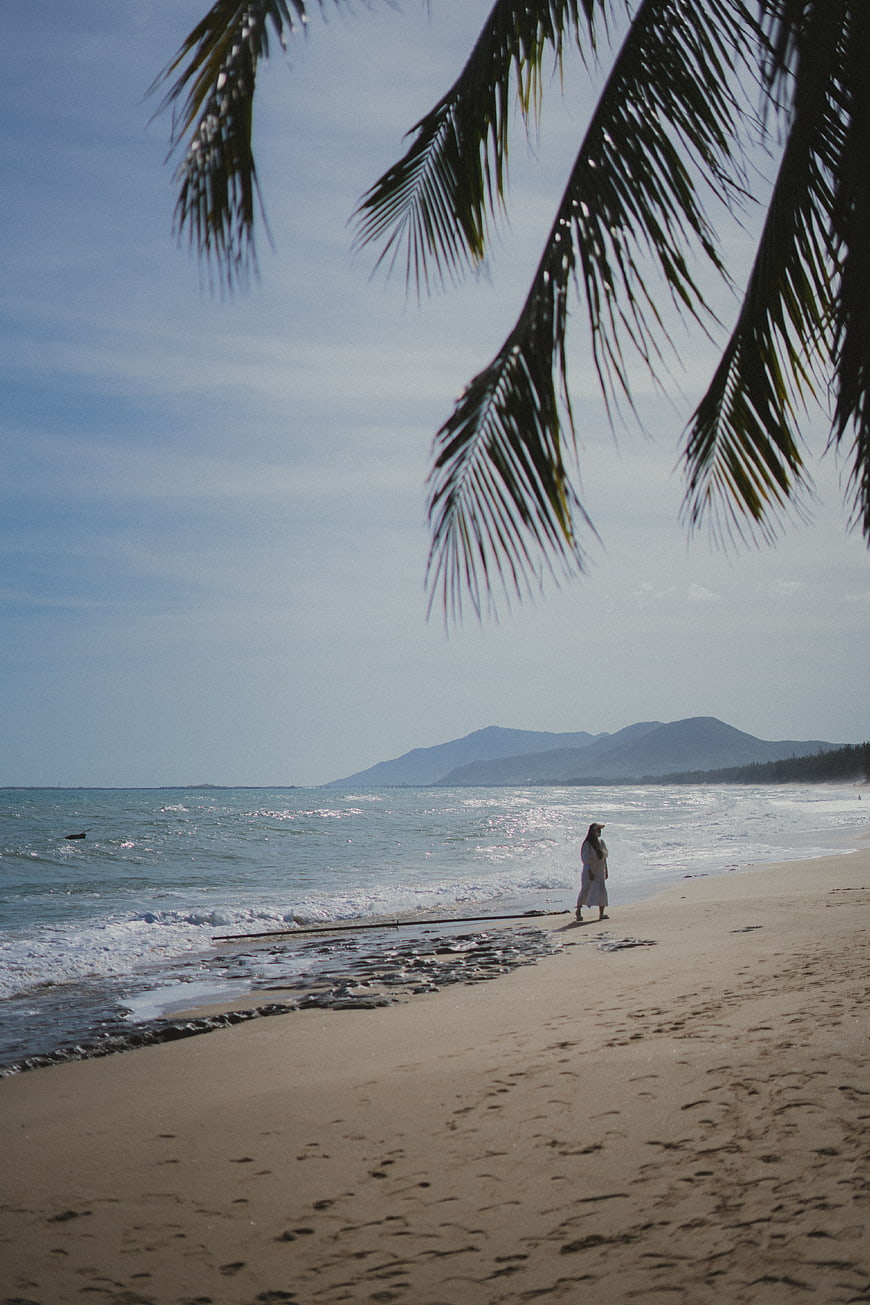 Woman Walking on Tropical Beach with Palm Leaves