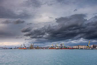Dramatic cloudy sky over industrial harbor with cranes and ships