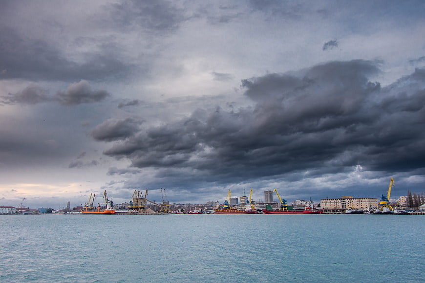 Dramatic cloudy sky over industrial harbor with cranes and ships