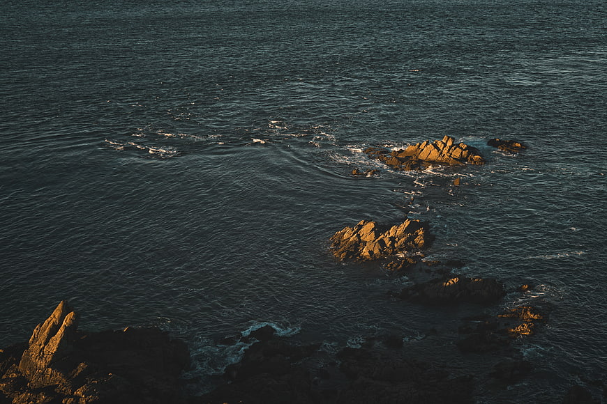 Aerial view of rocky coastline with golden hour sunlight