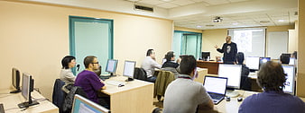 Professor teaching computer class to students in a university lab