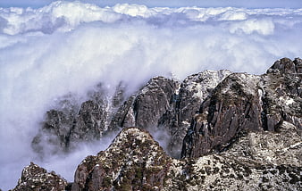 Rugged mountain peaks rising above a thick sea of clouds