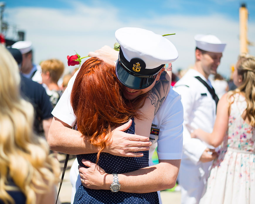 Navy sailor hugging red-haired woman at homecoming