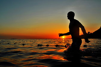 Silhouette of Man Running in Ocean at Sunset