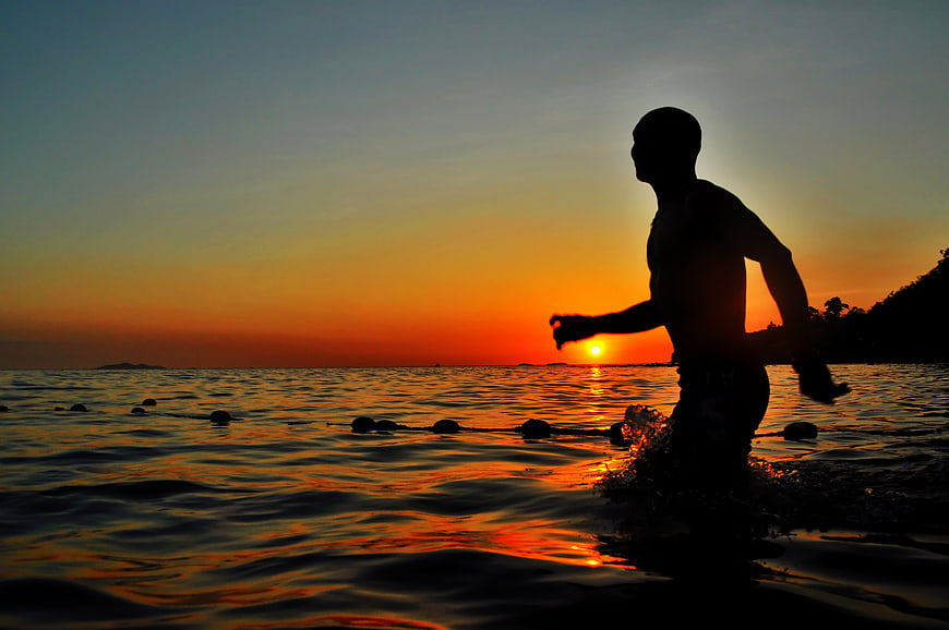 Silhouette of Man Running in Ocean at Sunset