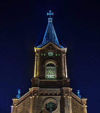 Illuminated Church Tower at Night with Star Trails