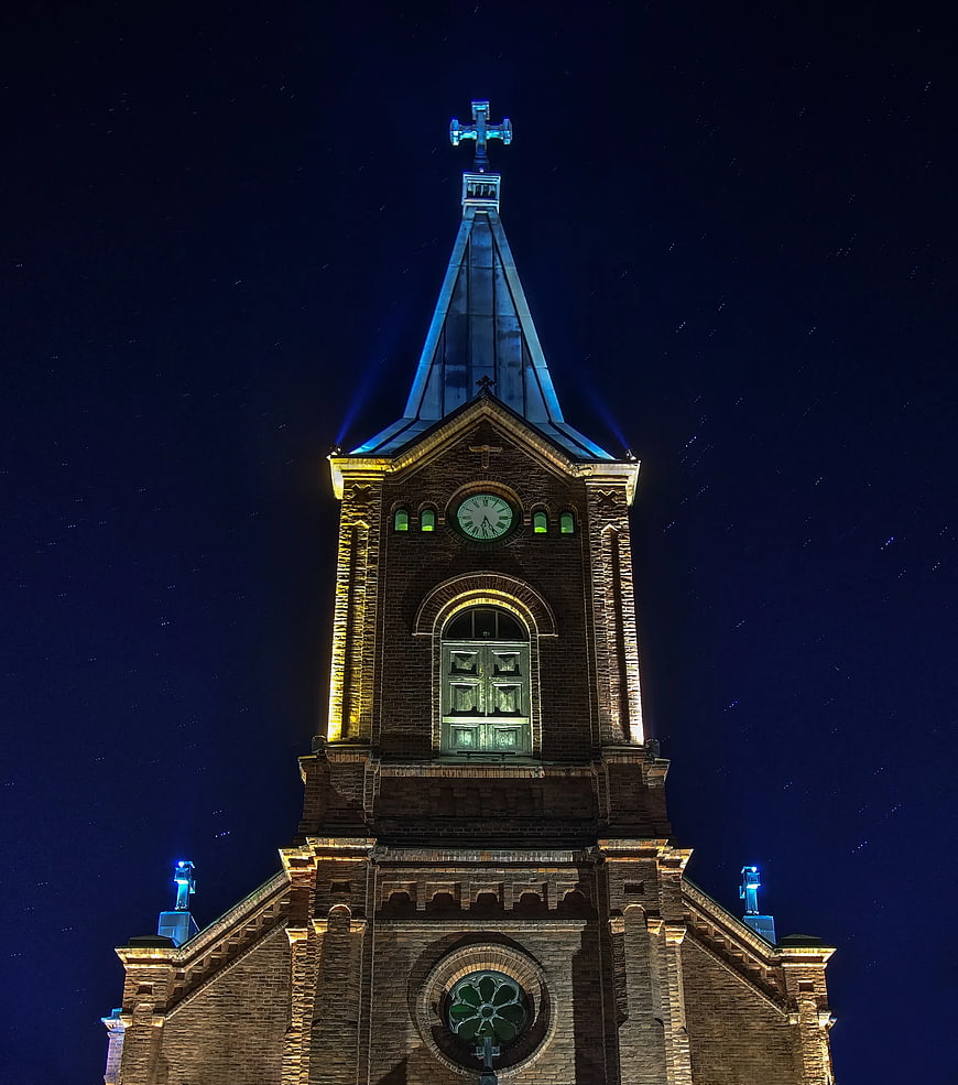 Illuminated Church Tower at Night with Star Trails
