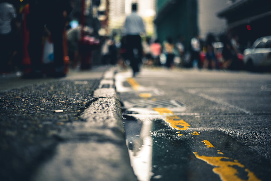 Low angle street view with puddle reflection and blurred city background