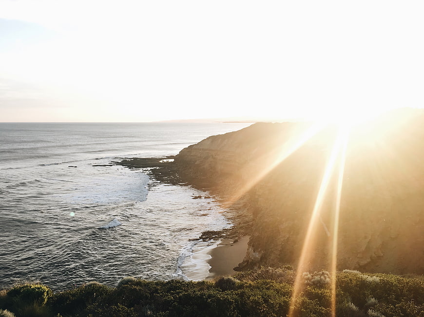Sunset over coastal cliffs with ocean waves and golden light