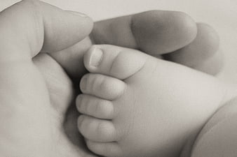 Close-up of Adult Hand Holding Newborn Baby Foot