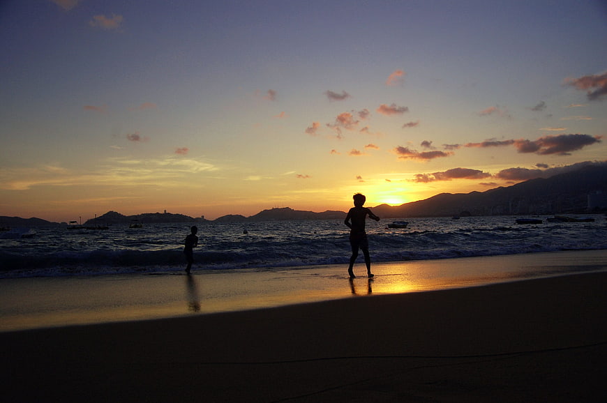Silhouettes of Children Playing on Beach at Sunset
