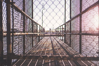 Metal pedestrian bridge with chain-link fences and sunlight