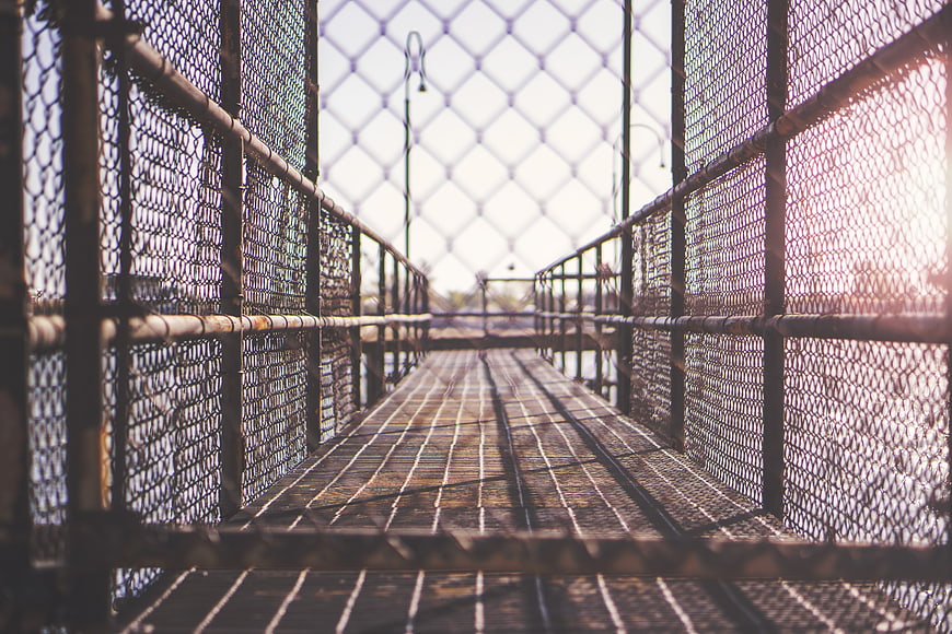 Metal pedestrian bridge with chain-link fences and sunlight