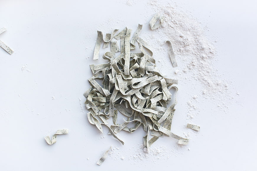 Fresh handmade pasta tagliatelle with flour on white background
