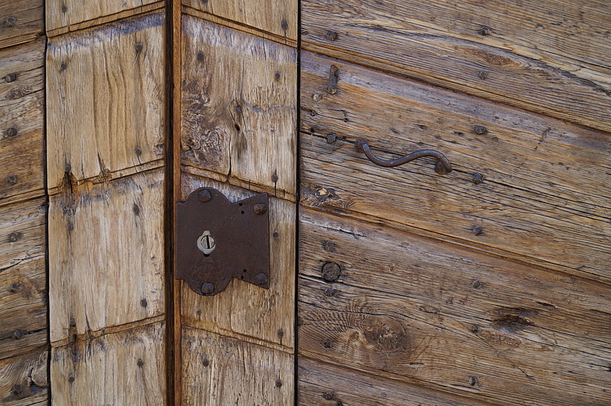 Close-up of weathered wooden door with vintage lock