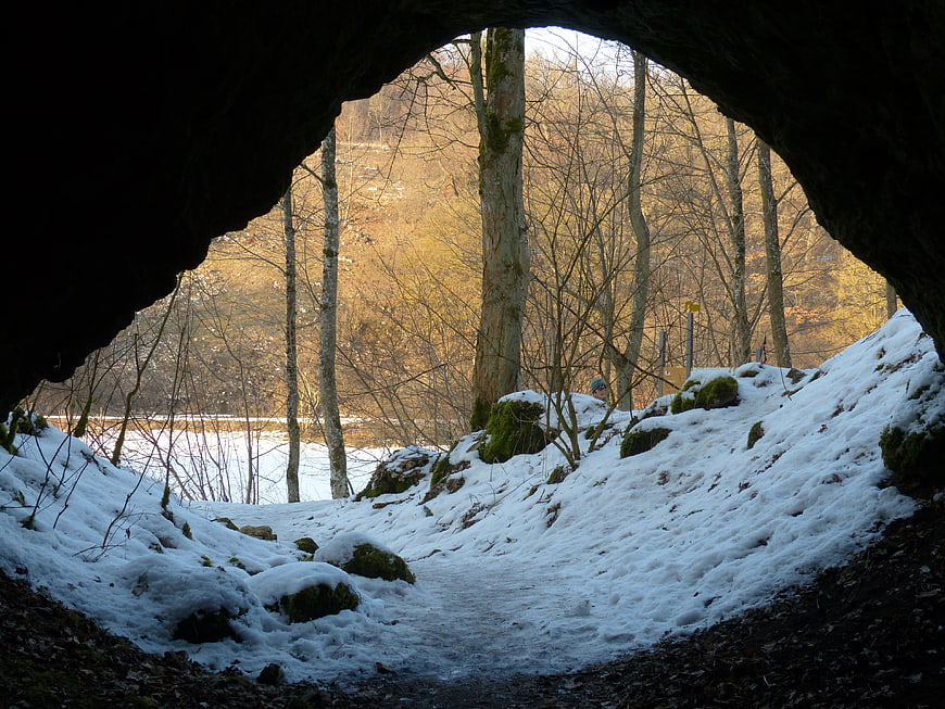 Snowy Forest Path Viewed Through Dark Cave Entrance