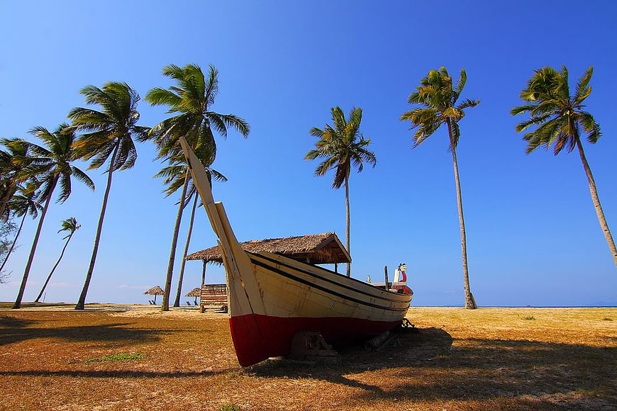 Traditional Wooden Boat on Tropical Beach with Palm Trees