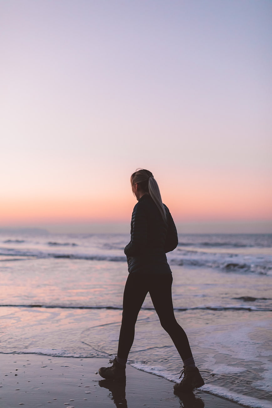 Silhouette of Woman Walking on Beach at Sunset