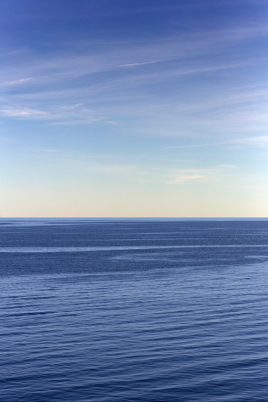 Serene Blue Ocean Horizon with Wispy Clouds