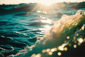 Golden sunlight reflecting on a crashing ocean wave