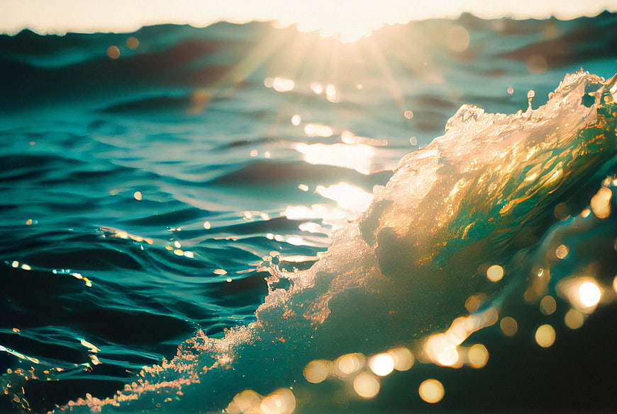 Golden sunlight reflecting on a crashing ocean wave