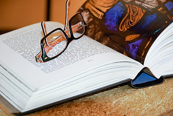 Black Eyeglasses Resting on Open Book with Text