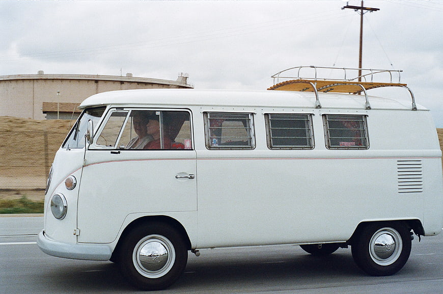 Vintage White Volkswagen Bus Driving on Highway