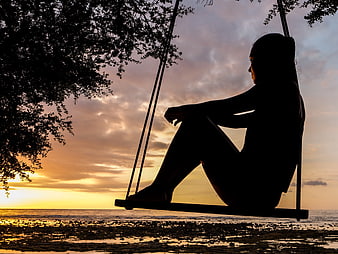 Silhouette of Woman on Beach Swing at Sunset