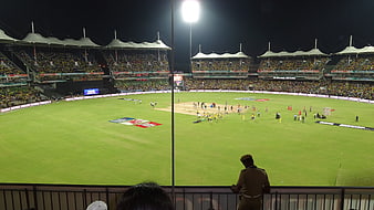 Wide Night View of Floodlit Cricket Stadium with Spectators