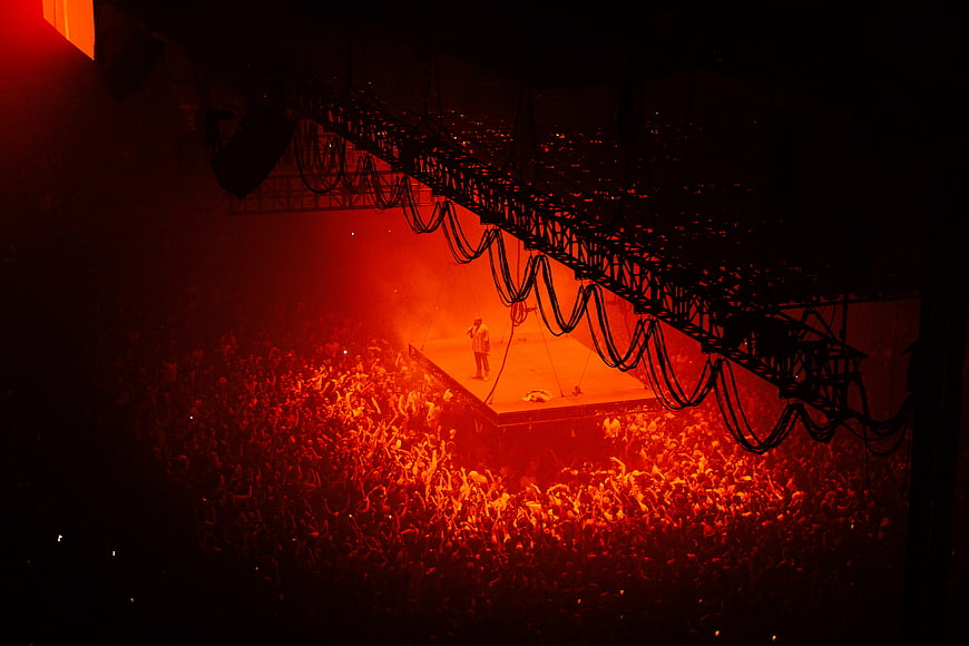 Concert crowd under red stage lights with performer