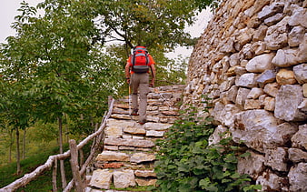 Hiker with backpack climbing stone steps in Lessinia, Italy