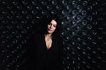 Woman in black standing before wine cellar wall