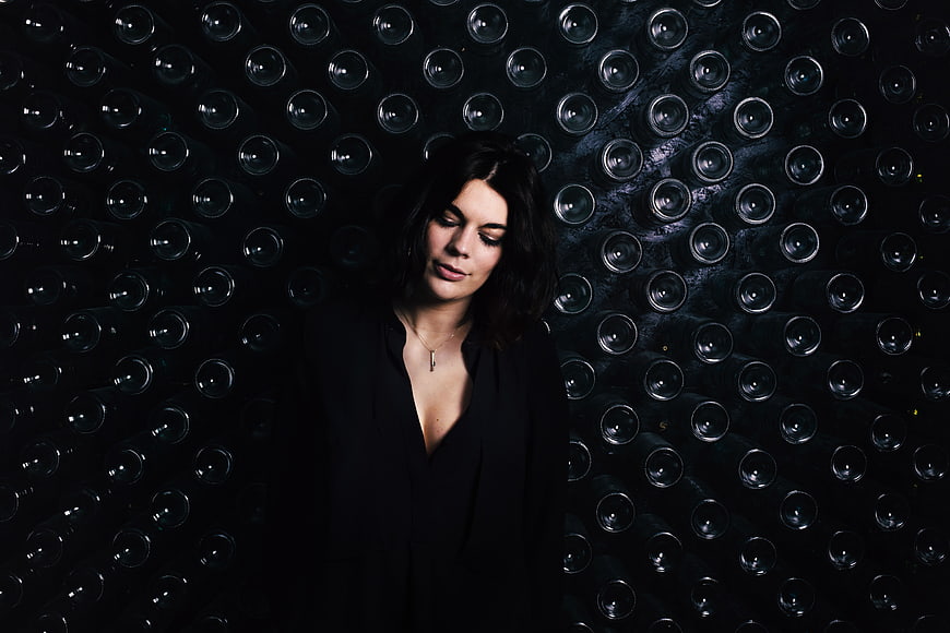 Woman in black standing before wine cellar wall