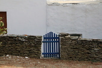 Blue wooden gate in stone wall with white building