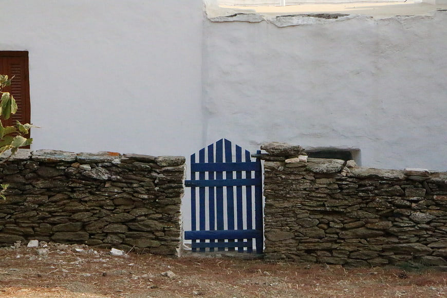 Blue wooden gate in stone wall with white building