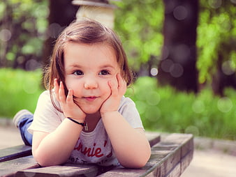 Cute Toddler Girl Lying on Park Bench in Summer