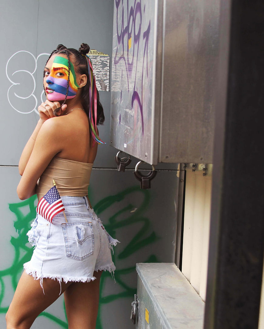 Woman with rainbow face paint and American flag in urban setting