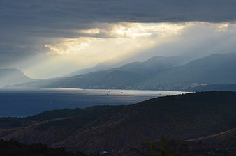 Dramatic sun rays over coastal mountains and sea landscape