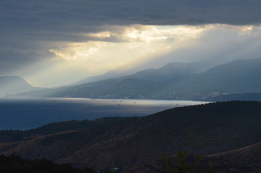 Dramatic sun rays over coastal mountains and sea landscape