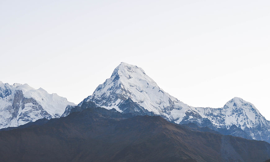Snow-capped mountain peak with dark foreground hills