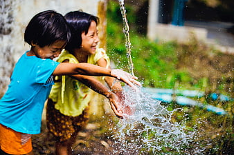 Two happy children playing with splashing water outdoors