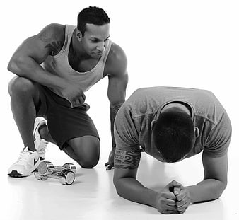 Personal trainer motivating exhausted client during gym workout
