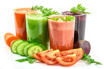Fresh vegetable juices with sliced carrots, cucumbers, tomatoes, and beets