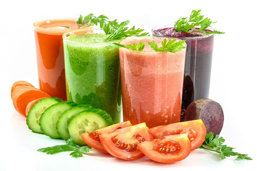 Fresh vegetable juices with sliced carrots, cucumbers, tomatoes, and beets