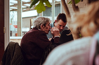 Senior man and younger man talking in cafe